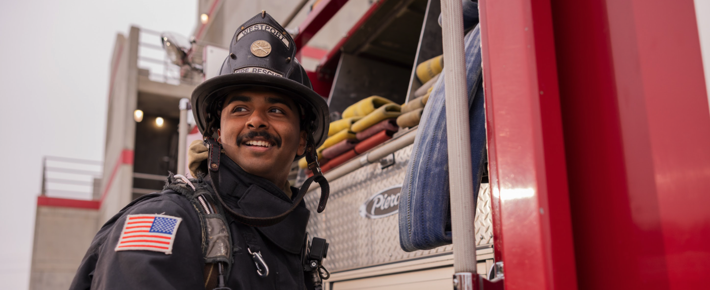 Fireman with gear on looking back smiling on a job well done.